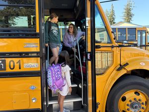 Image: School bus and students in front of a school building