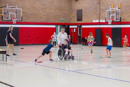 An instructional aide pushes Harper Costa, a student at Columbia Elementary, in her wheelchair so she can play dodgeball with her classmates