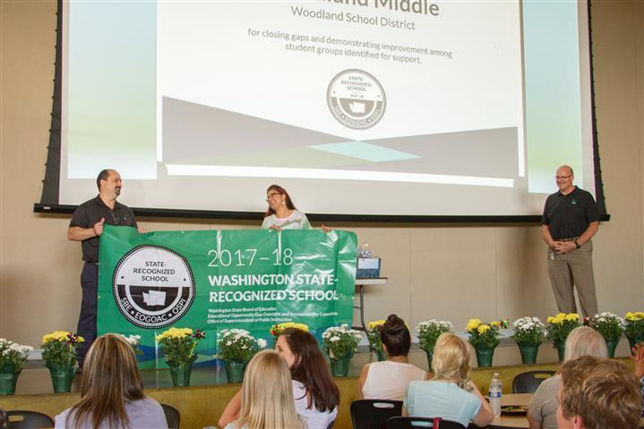 Principal James and Asha Riley hold up recognition banner